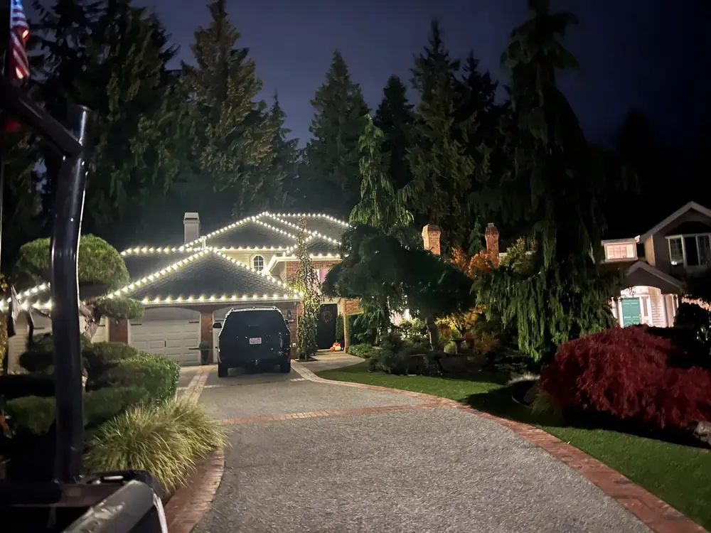 Warm white roofline lights on a home set back from a long driveway