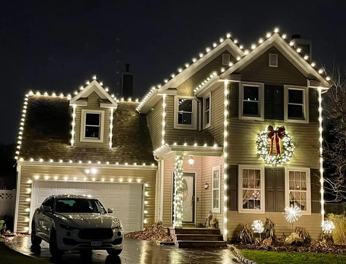 Home lit with warm white C9 roofline lights and a wreath